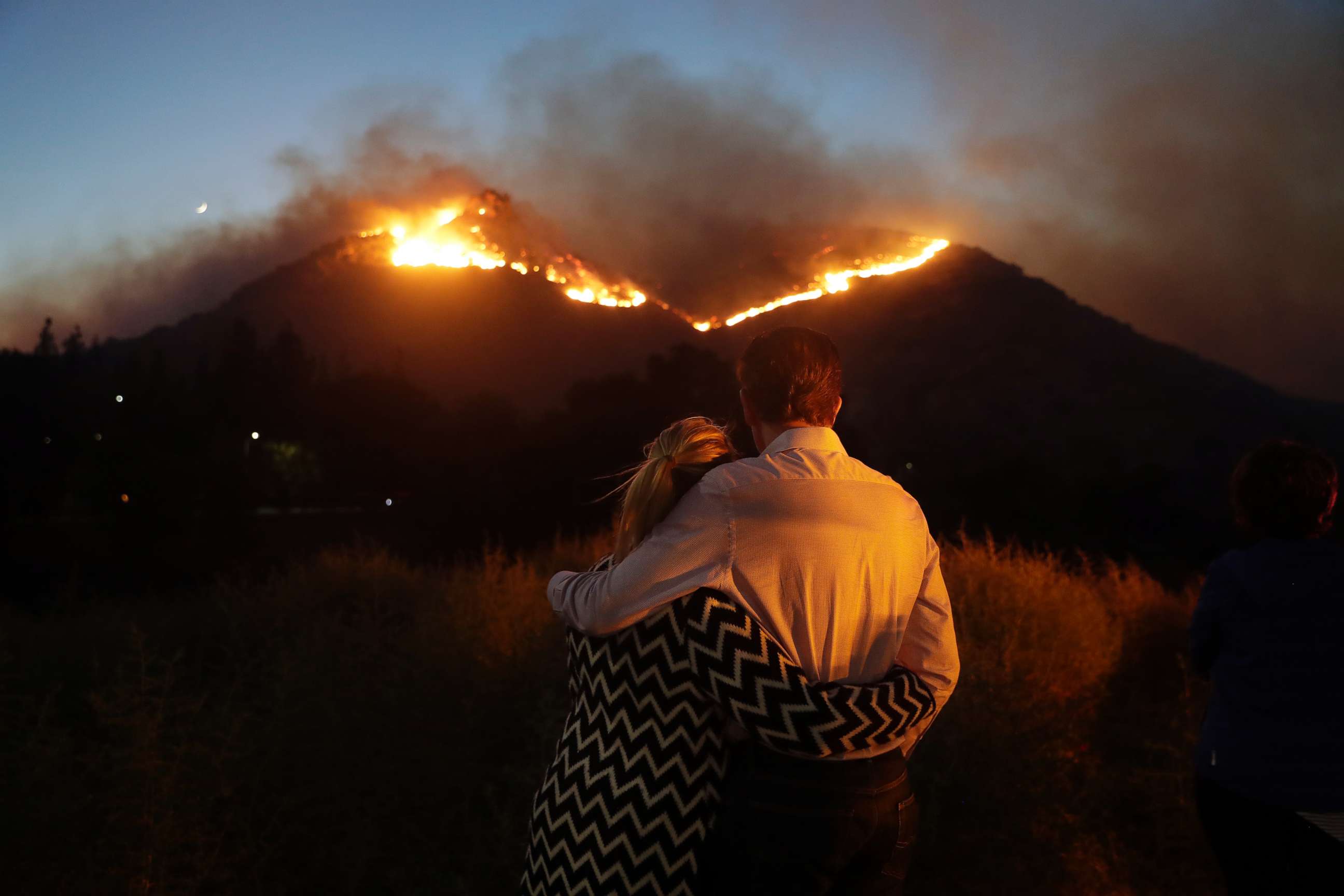 PHOTO: Roger Bloxberg, right, and his wife Anne hug as they watch a wildfire on a hill top near their home, Nov. 9, 2018, in West Hills, Calif. 