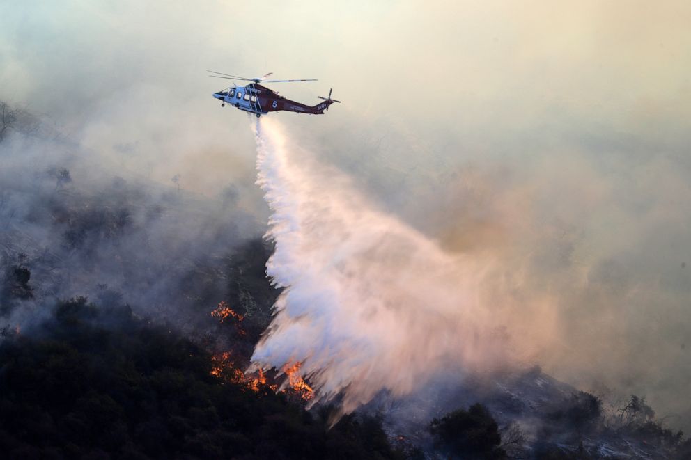 PHOTO: A helicopter drops water as the Getty fire burns on Mandeville Canyon, Oct. 28, 2019, in Los Angeles. 