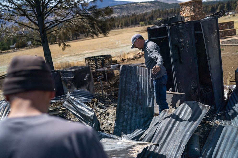 PHOTO: Travis Hopkins looks for salvageable objects at a historic barn that was burned down at his home after a wildfire burned through parts near Highway 89 in northeast Flagstaff, Ariz., on April 24, 2022.
