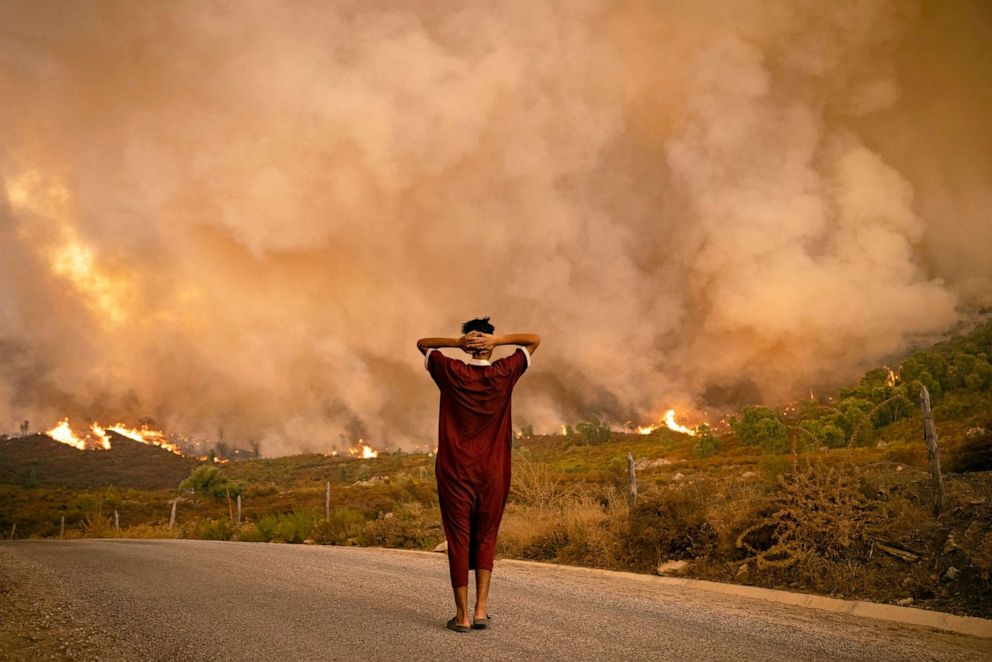 PHOTO: A woman looks at wildfires tearing through a forest in the region of Chefchaouen in northern Morocco, Aug. 15, 2021.