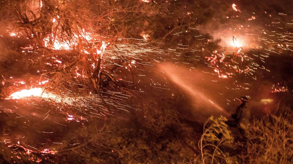 PHOTO: A man uses a hose to extinguish the Creek Fire as it burns along a hillside near homes and horses in the Shadow Hills neighborhood of Los Angeles, Calif., on Dec. 5, 2017.
