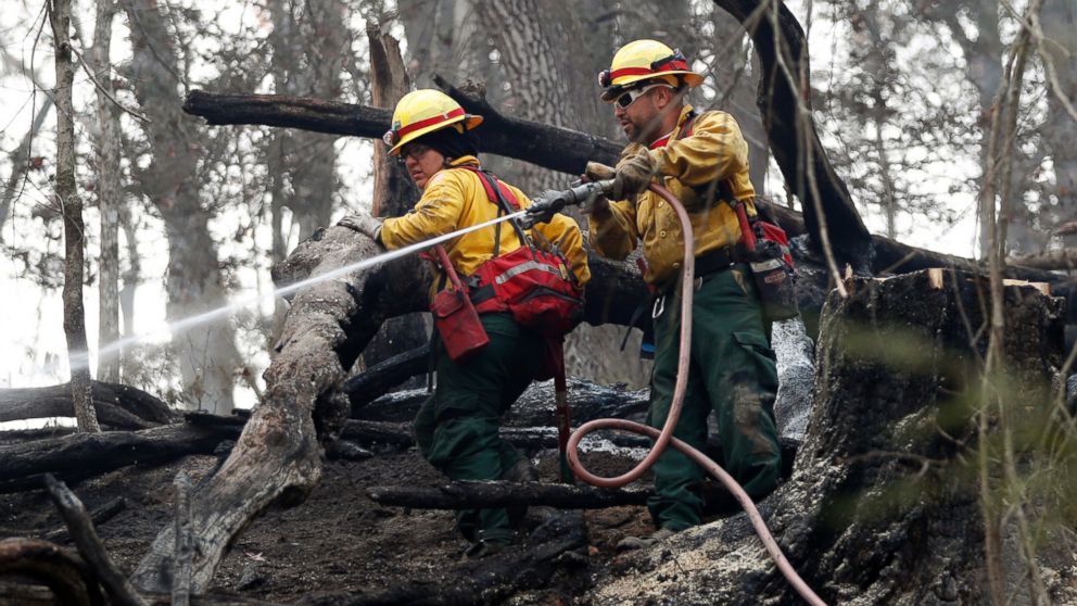 PHOTO: Firefighters Valarie Lopez, left, and Mark Tabaez work to cool hot spots after a wildfire burned a hillside, Nov. 15, 2016, in Clayton, Georgia.