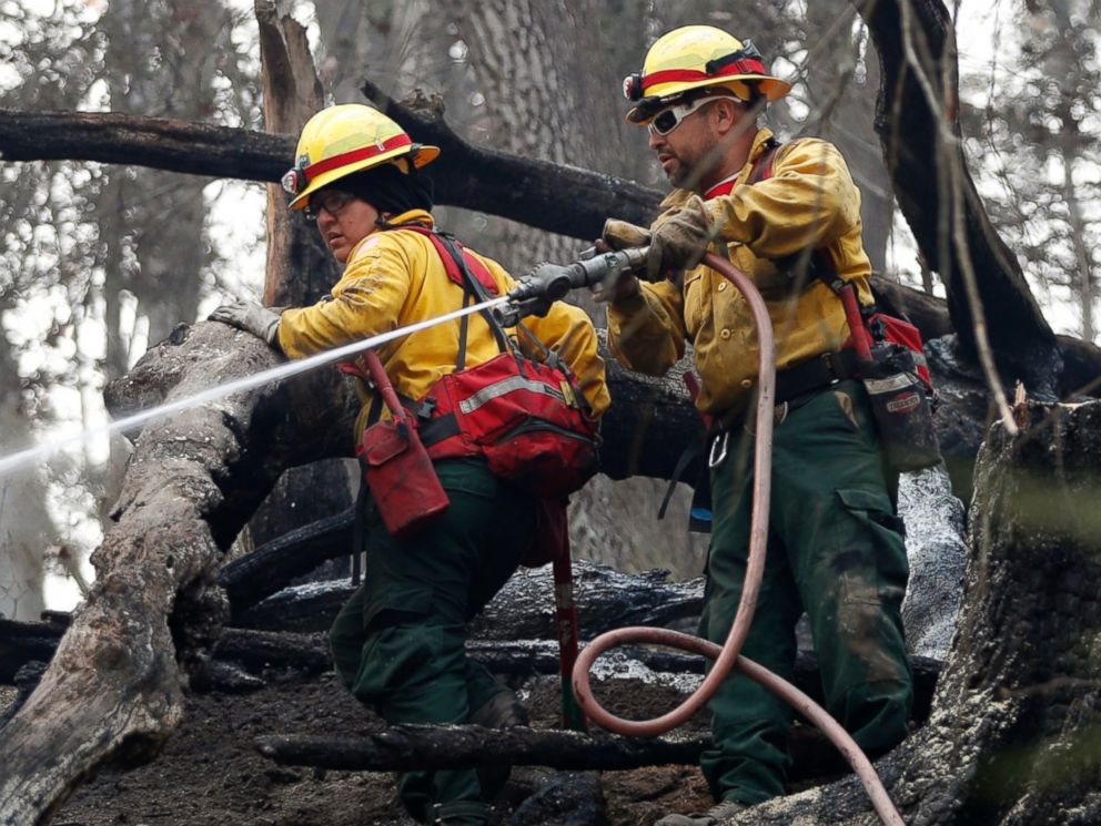 PHOTO: Firefighters Valarie Lopez, left, and Mark Tabaez work to cool hot spots after a wildfire burned a hillside, Nov. 15, 2016, in Clayton, Georgia.