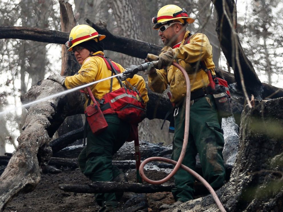 PHOTO: Firefighters Valarie Lopez, left, and Mark Tabaez work to cool hot spots after a wildfire burned a hillside, Nov. 15, 2016, in Clayton, Georgia.