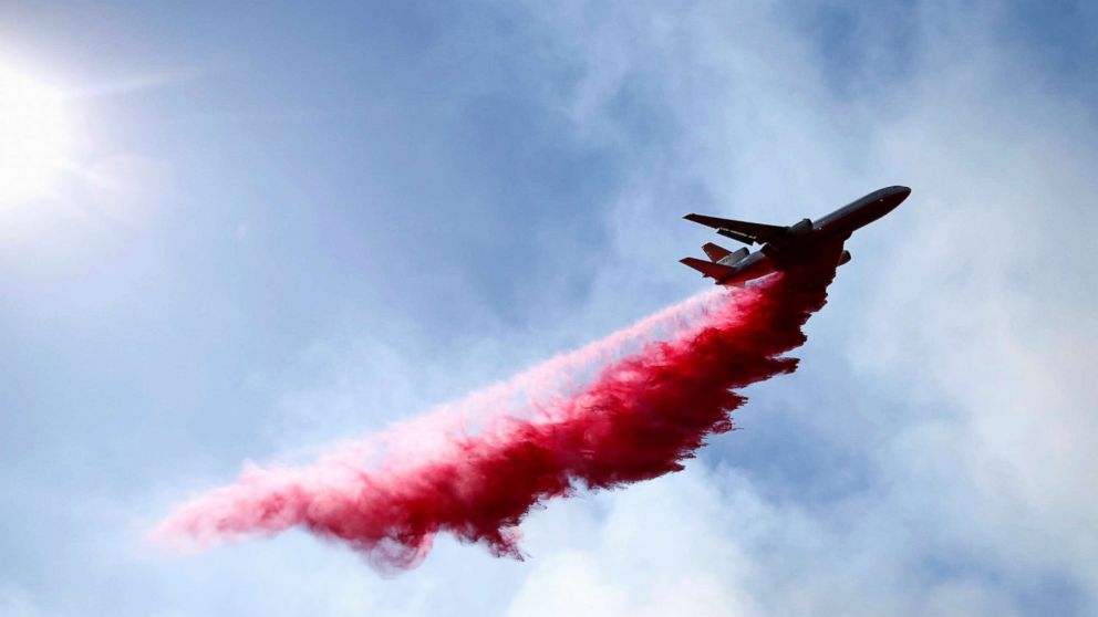 PHOTO: An aircraft drops flame retardant as firefighters battle the Woolsey Fire as it continues to burn in Malibu, Calif., Nov. 11, 2018. 