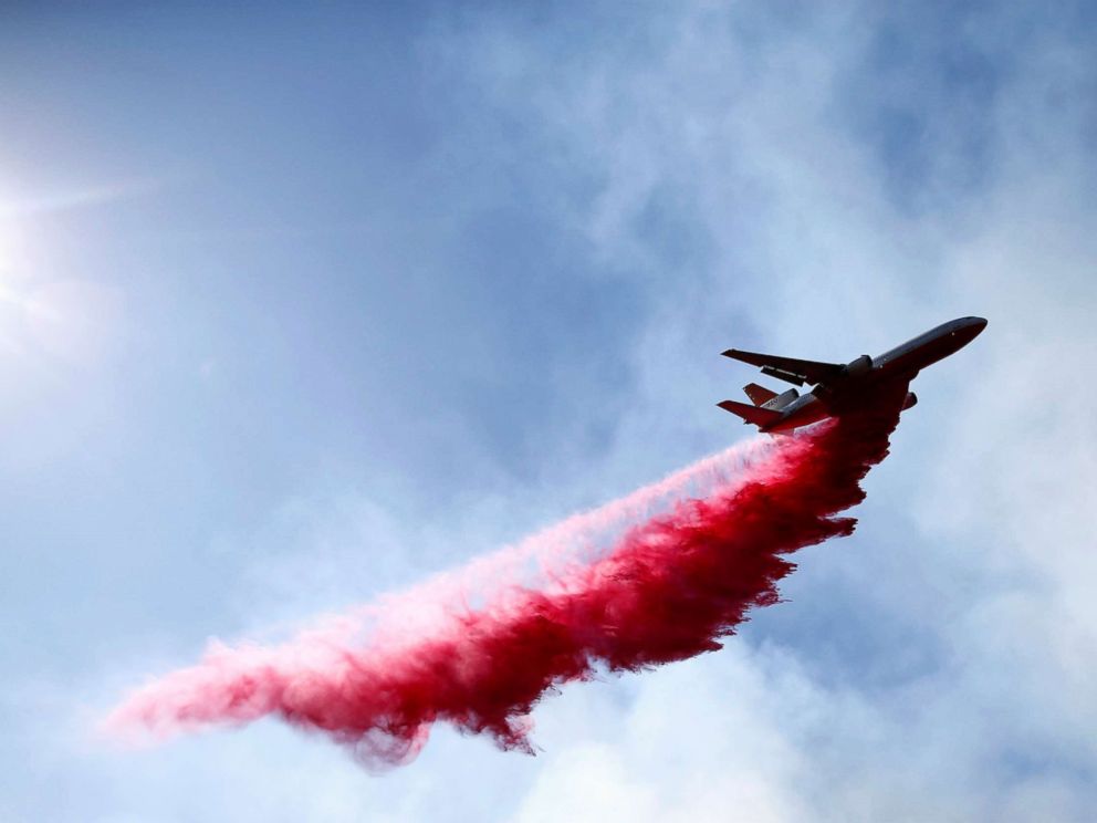 PHOTO: An aircraft drops flame retardant as firefighters battle the Woolsey Fire as it continues to burn in Malibu, Calif., Nov. 11, 2018. 