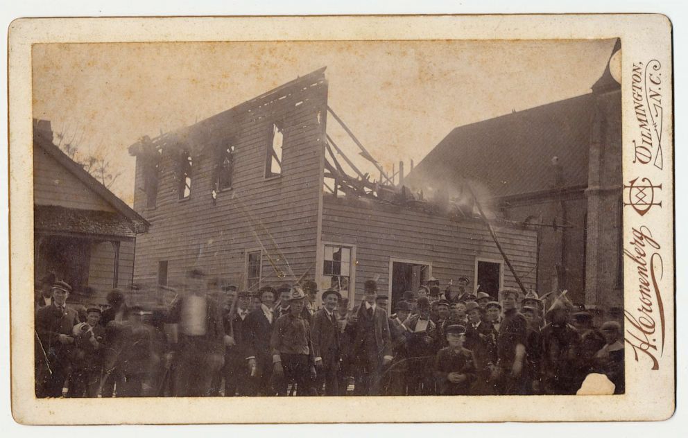 PHOTO: Men stand in front of The Daily Record, the only Black newspaper, after burning it to the ground