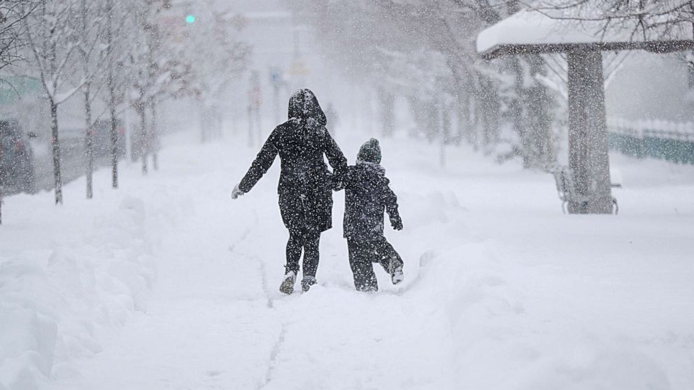 PHOTO: A mom and her child run in the snow storm on Memorial Drive in Cambridge, Mass., on Jan. 7, 2022. 