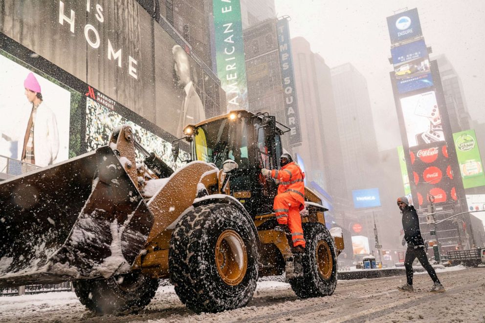 PHOTO: City workers clear streets as pedestrians walk through a snowstorm in Times Square, Feb. 1, 2021, in New York City.