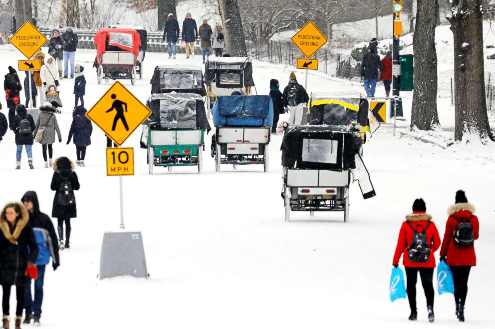 PHOTO: Park-goers and pedi-cabs fill the roadway during a light snow in New York's Central Park, Dec. 30, 2017.  