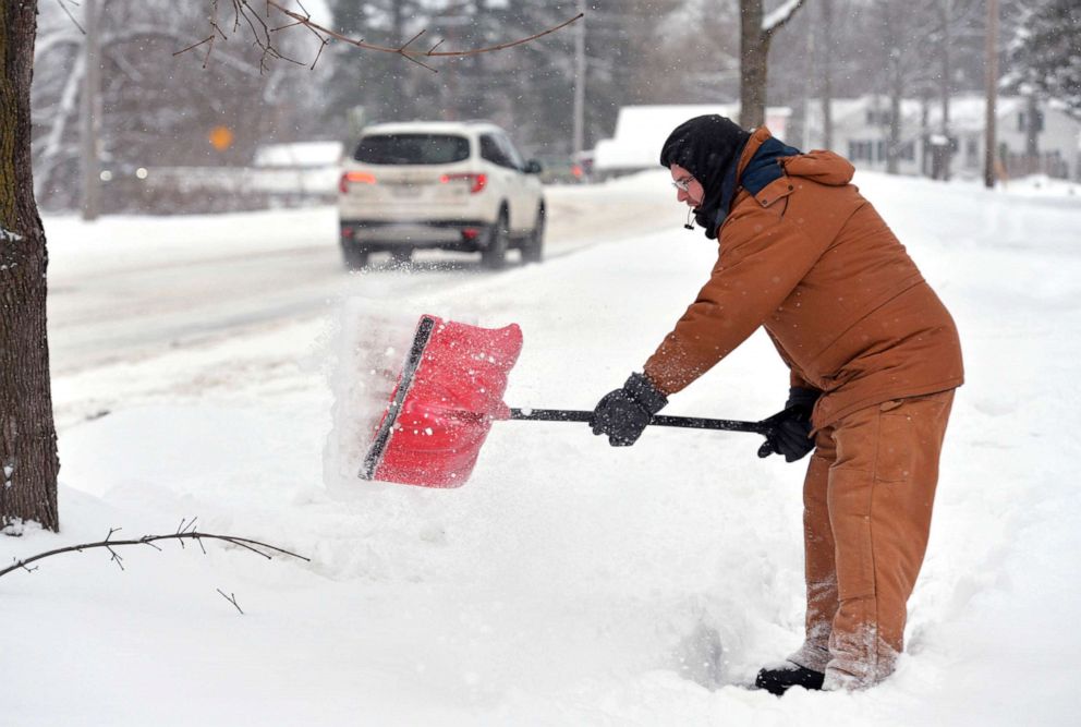 PHOTO: Kris Hromek clears snow from the sidewalk in front of his home on Wednesday, Dec. 18, 2019, in Wattsburg, Pa.
