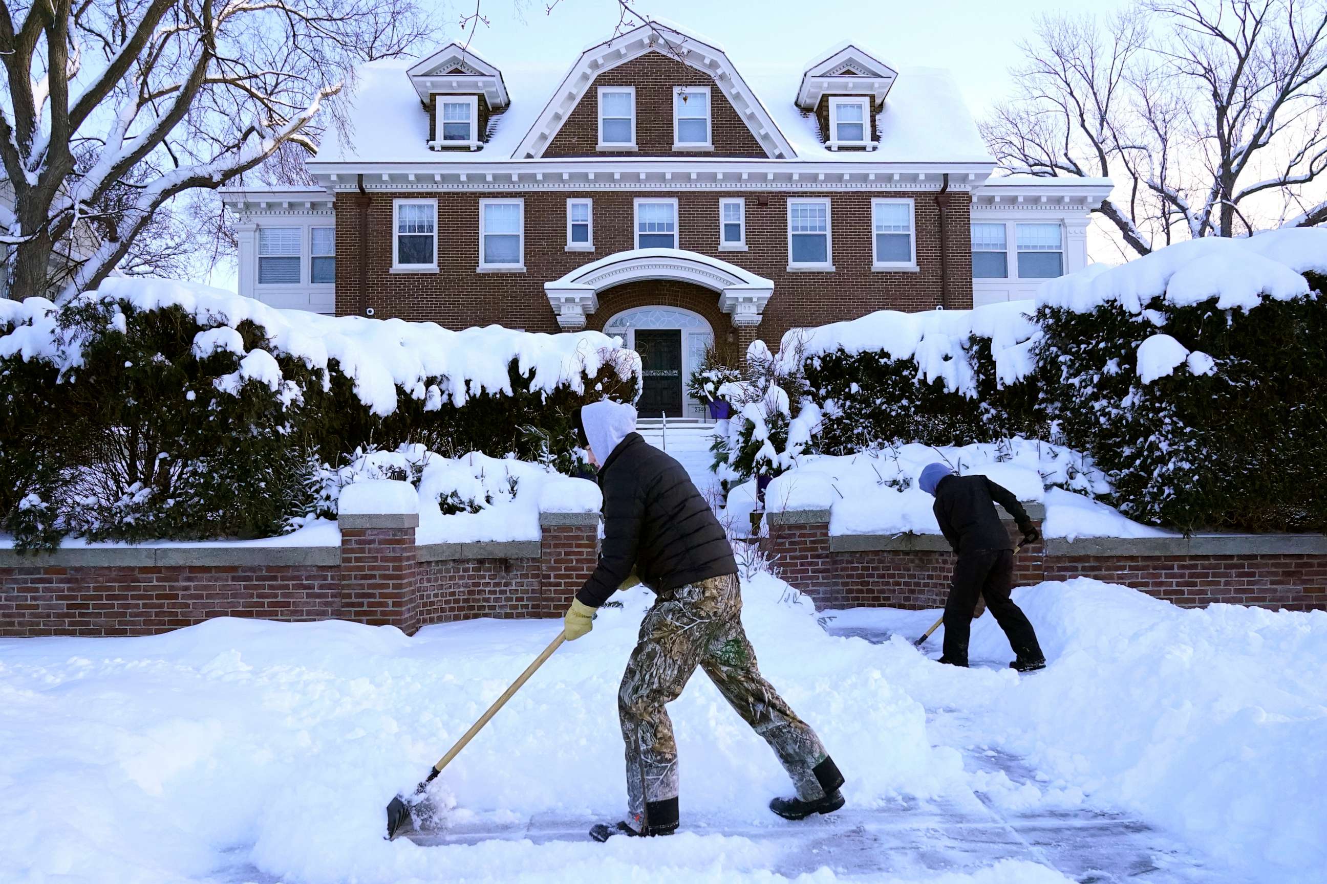 PHOTO: Kids shovel snow off a sidewalk and driveway Dec. 22, 2022, in Minneapolis.