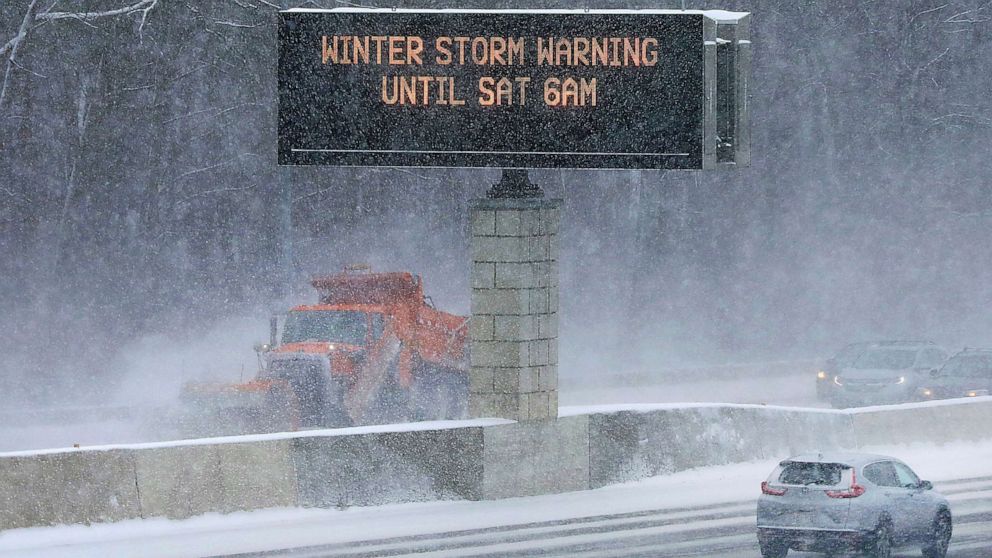 Photo: Traffic and snowplow vehicles clear the roadway as traffic signs warn drivers of road conditions along State Route 14/18 in Madison, Wisconsin, December 22, 2022.