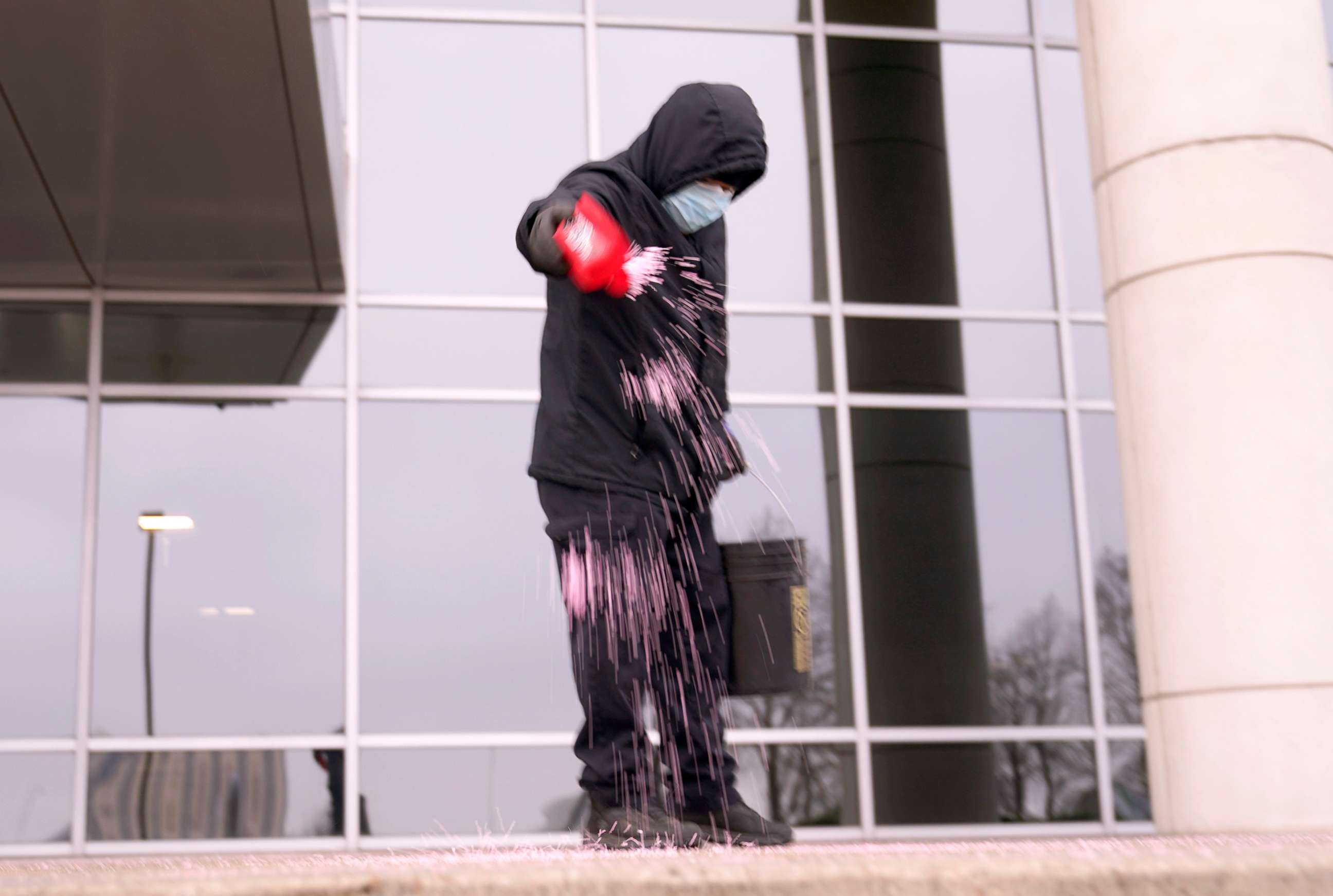 PHOTO: Humberto Torres spreads ice melting pellets on the steps of an office building in Richardson, Texas. A winter storm brought a coating of ice to parts of Texas, Feb. 11, 2021 