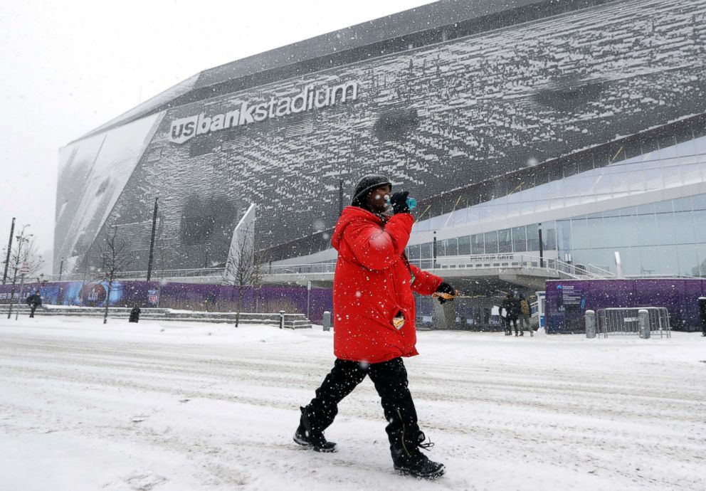 PHOTO: A woman takes a drink as she walks in the snow past U.S. Bank Stadium, Feb. 3, 2018, in Minneapolis.