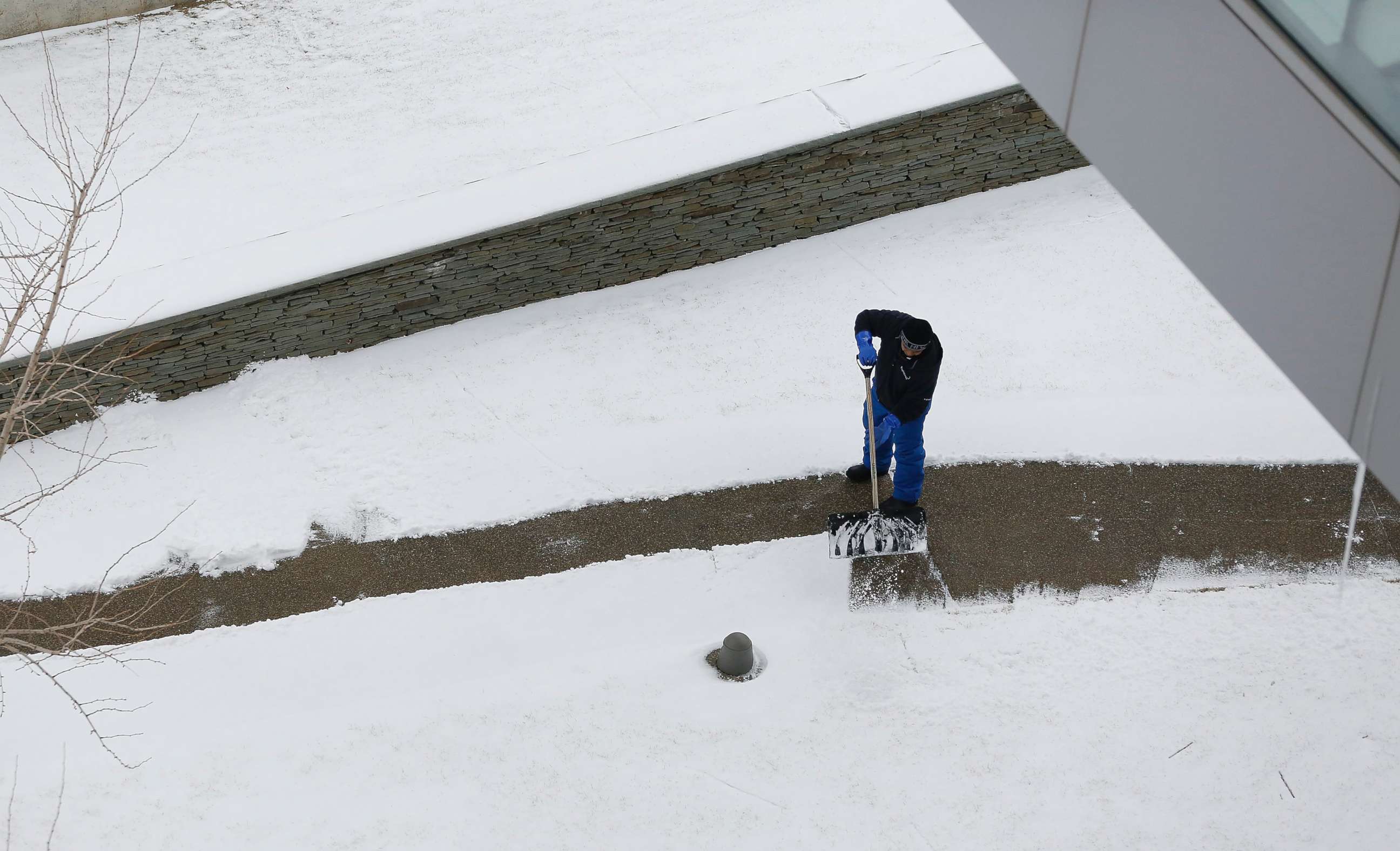 PHOTO: A Massport employee clears snow on a walk way at Boston Logan International Airport, Jan. 30, 2018, in Boston. A late January snowstorm left two inches in the greater Boston area and caused several delays at the airport.  