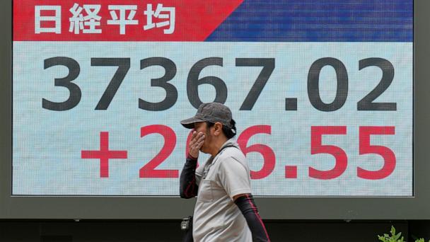 A person walks in front of an electronic stock board showing Japan's Nikkei index at a securities firm Monday, May 26, 2025, in Tokyo. (AP Photo/Eugene Hoshiko)