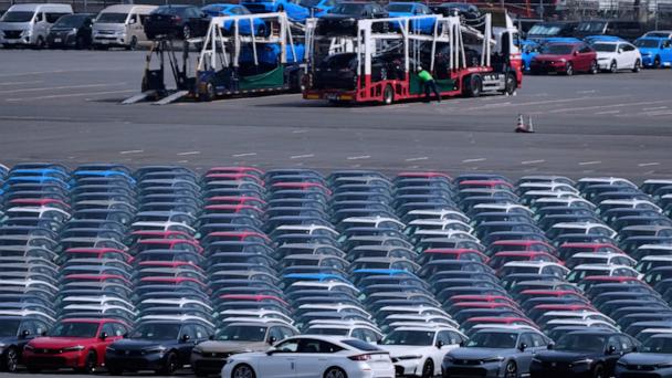 FILE - Workers, back, unload vehicles while a car, center front, is moved to another location of the area, where export vehicles are parked at the Daikoku vehicle terminal center in Yokohama, near Tokyo, April 8, 2025. (AP Photo/Hiro Komae, File)