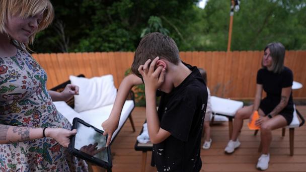 Charlie Lamb, who is diagnosed with autism and is non-verbal, uses an AAC device to communicate with a caregiver, Monday, May 12, 2025, in Austin, Texas. (AP Photo/Eric Gay)