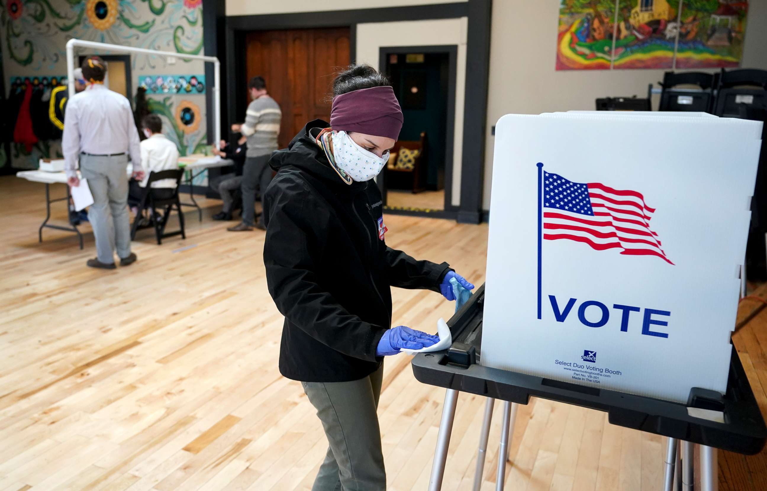 PHOTO: Shanon Hankin, cleans a voter booth after it was used for voting at the Wil-Mar Neighborhood Center, April 7, 2020 in Madison, Wis.