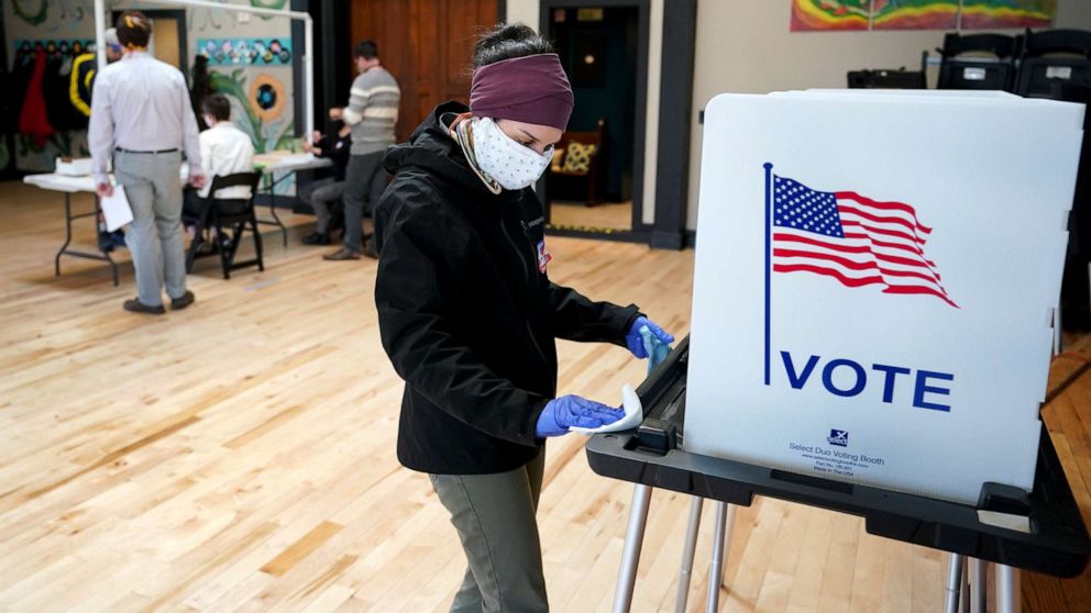 PHOTO: Shanon Hankin, cleans a voter booth after it was used for voting at the Wil-Mar Neighborhood Center,  April 7, 2020 in Madison, Wis.