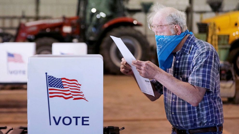 PHOTO: Robert Wilson reviews his selections on his ballot while voting at the town's highway garage building, April 7, 2020, in Dunn, Wis.