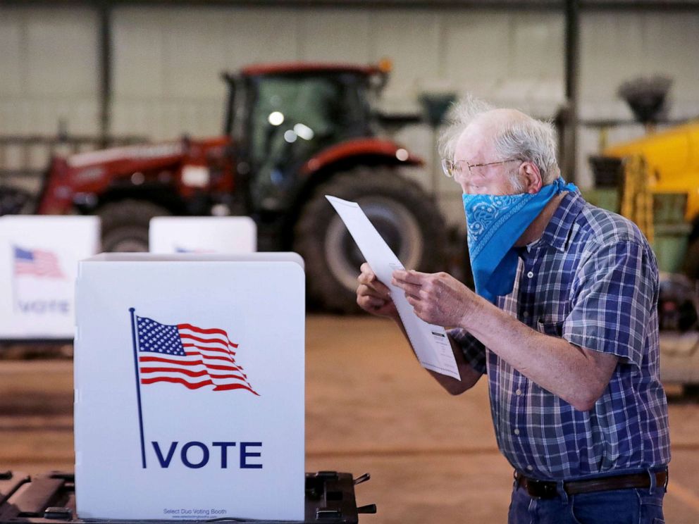 PHOTO: Robert Wilson reviews his selections on his ballot while voting at the town's highway garage building, April 7, 2020, in Dunn, Wis.