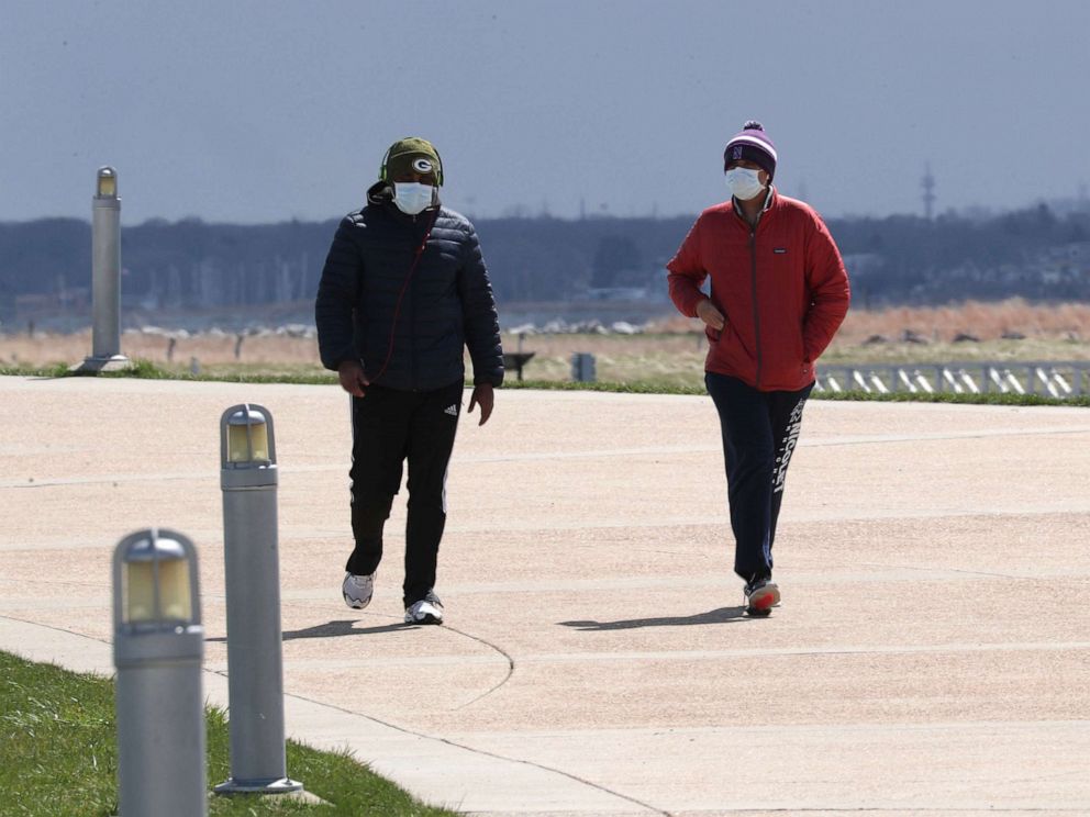 PHOTO: People wearing face masks walk through Lakeshore State Park in Milwaukee, April 9, 2020.  