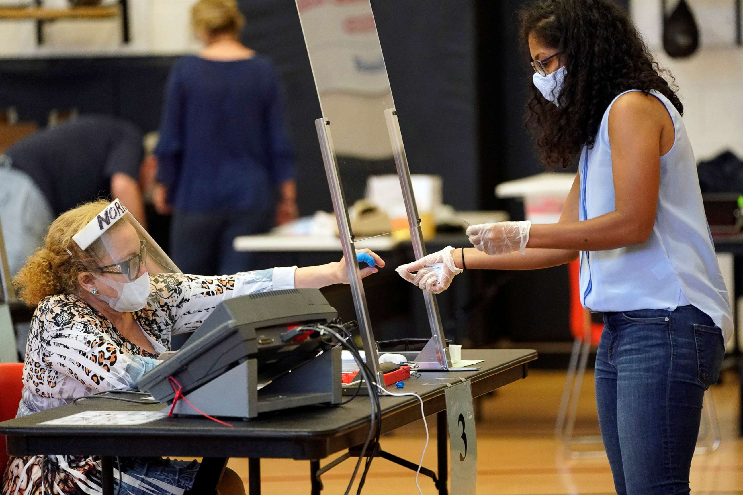 PHOTO: Harris County election clerk Nora Martinez helps a voter casting her ballot during early voting for the Texas primary runoffs on June 29, 2020 in Houston.