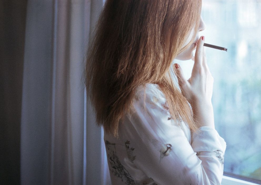 PHOTO: A woman stands by the window smoking a cigarette in this undated stock photo.