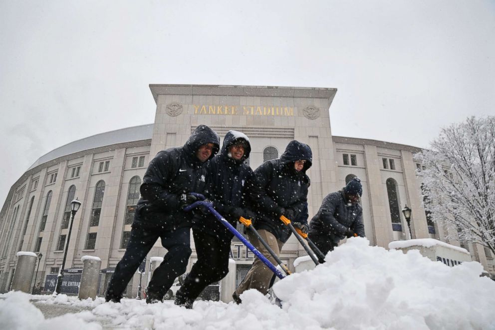 PHOTO: Men shovel snow from the sidewalks in front of Yankee Stadium before the New York Yankees home opener against the Tampa Bay Rays, April 2, 2018, in New York. 