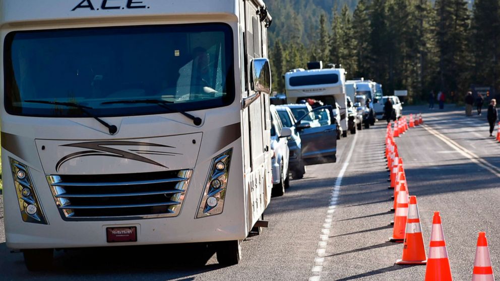 PHOTO: Dozens of vehicles line up outside the entrance to Yellowstone National Park near Wapiti Wyo on June 22, 2022. The park is partially reopening after being forced to close last week when record flooding caused extensive damage .