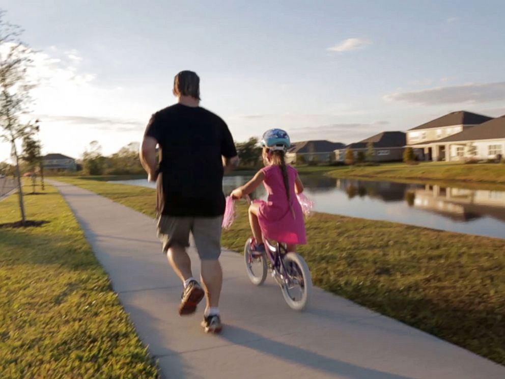 PHOTO: Buddy Rich runs alongside his daughter as she rides her bicycle. An accident that crushed his legs and hip, led to severe depression. His daughter, born shortly before, helped keep him from committing suicide, and yoga helped him heal.