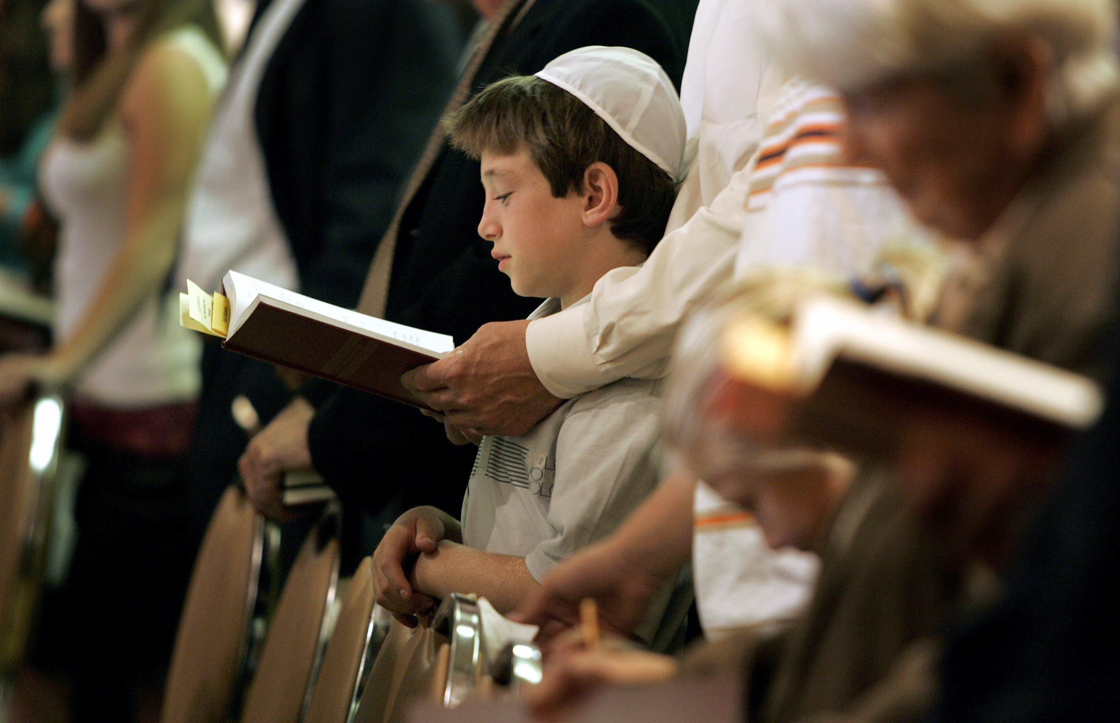 PHOTO: Eric Alperin, 9, of Pacific Palisades, follows along as his father, Jeff, holds the prayer book during the Kol Nidre service marking Yom Kippur at University Synagogue in Brentwood, Calf.