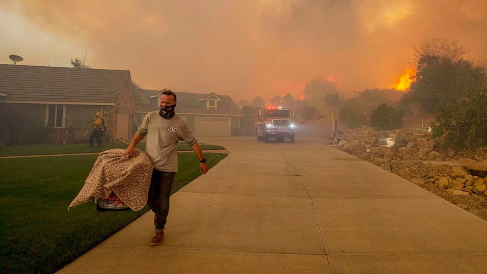 PHOTO: Smoke fills the skies as a neighbor helps a family remove animals from their home while the El Dorado fire burns close to a house in Yucaipa, Calif., Sept. 6, 2020.