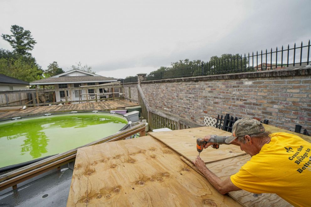 PHOTO: Will Schwander screws in a plywood shelter to protect patio furniture as Hurricane Zeta approaches on Oct. 28, 2020, in Arabi, La.