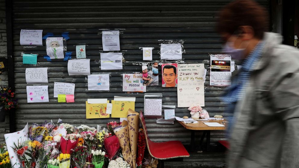 A person walks past a memorial for food delivery courier Zhiwen Yan, a 45-year-old Chinese immigrant who was shot and killed on April 30, 2022, outside the Chinese restaurant where he worked in the Forest Hills neighborhood of Queens, New York on May 4, 2022.
