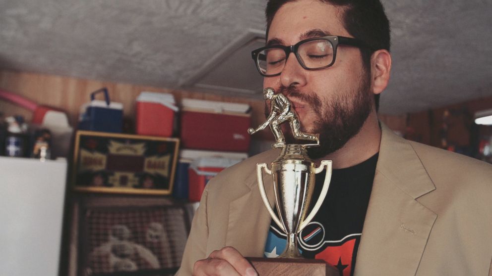 PHOTO: Skee-Ball champion Roy "Brewbacca" Hinojosa wearing his cream-colored jacket and kissing his trophy in Austin, Texas. 