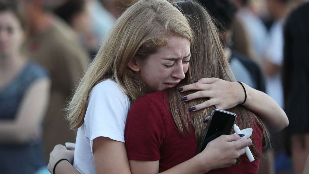 PHOTO: People hug as they attend a candlelit memorial service for the victims of the shooting at Marjory Stoneman Douglas High School that killed 17 people, Feb. 15, 2018, in Parkland, Fla.