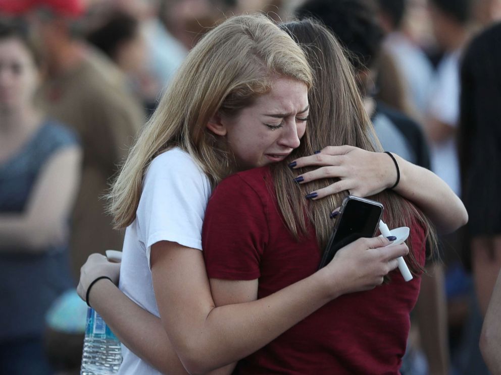 PHOTO: People hug as they attend a candlelit memorial service for the victims of the shooting at Marjory Stoneman Douglas High School that killed 17 people, Feb. 15, 2018, in Parkland, Fla. 