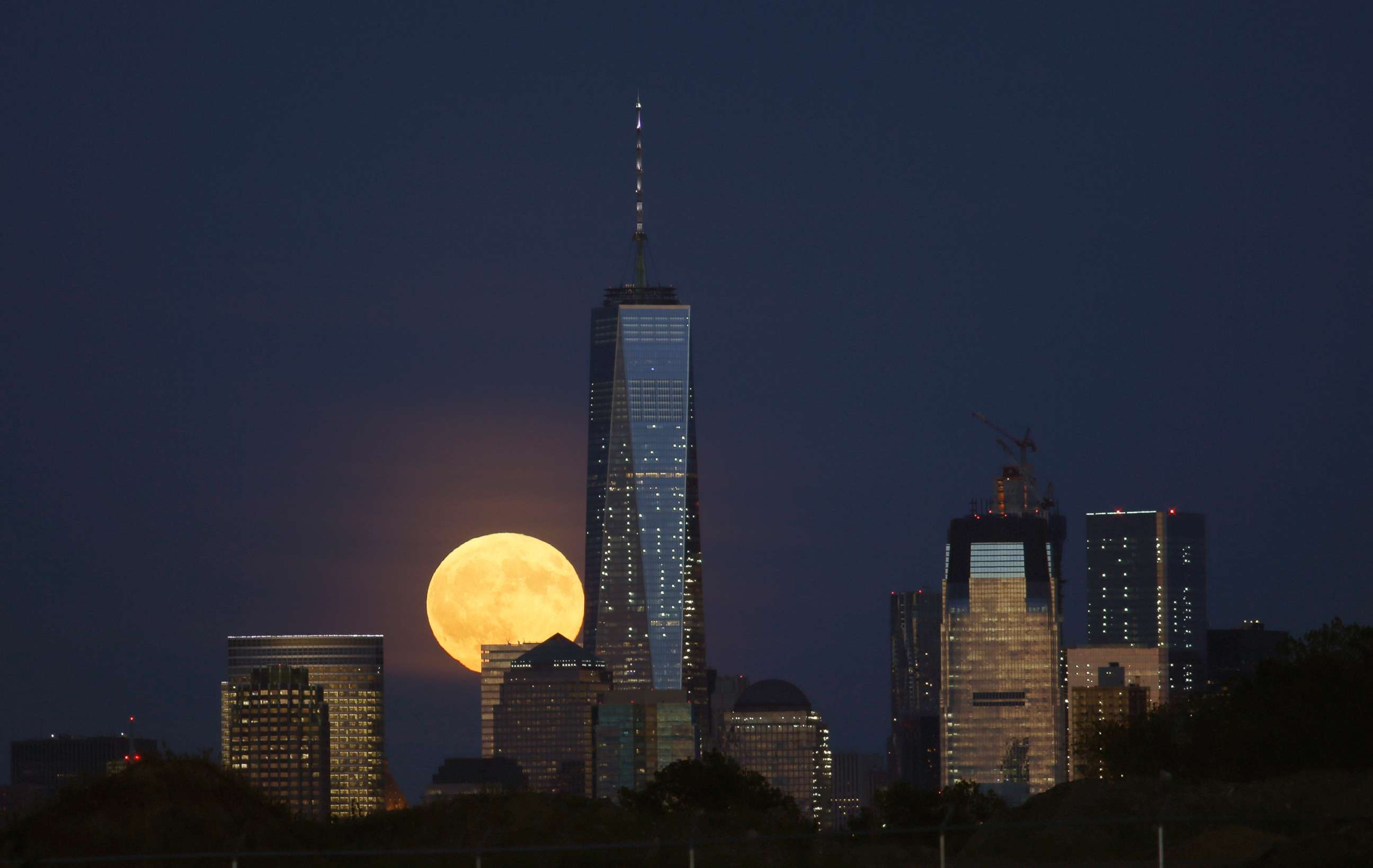 PHOTO: A full harvest moon rises behind Lower Manhattan and One World Trade Center in New York City, Sept. 16, 2016 as seen from Newark, N.J. 