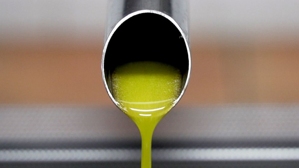 PHOTO: Freshly crushed olive oil is emerging from a small press prior to bottling.