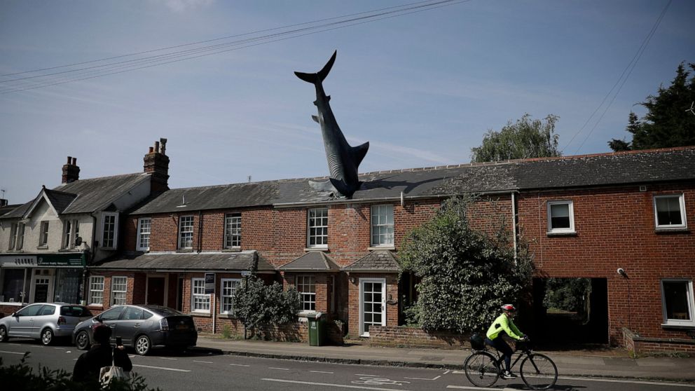 FILE - A fibreglass sculpture known as the Headington Shark and originally called "Untitled 1986", by British sculptor John Buckley stands appearing to crash through the roof of a house in the Headington area of Oxford, England, on April 30, 2019. Th