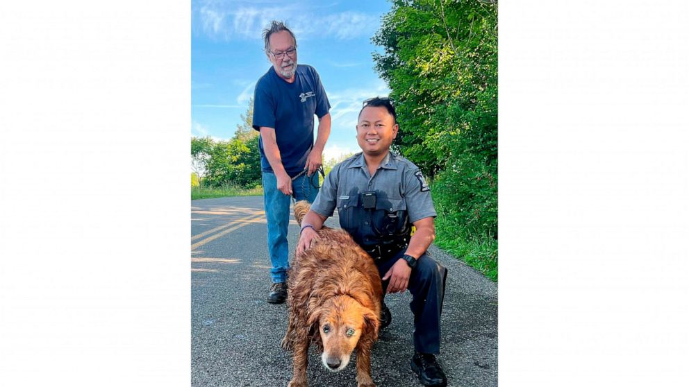 In this image provided by the New York State Police, Trooper Jimmy Rasaphone, right, poses for a photo with 13-year-old golden retriever Lilah, and her owner Rudy Fuehrer, after the trooper rescued her from a culvert pipe in Conklin, NY., on Sunday, 