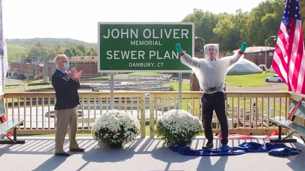 This image taken from video released by HBO shows John Oliver, host of "Last Week Tonight with John Oliver," right, with Mayor Mark Boughton during a dedication ceremony for The John Oliver Memorial Sewer Plant, in Danbury, Conn. Oliver made a secret