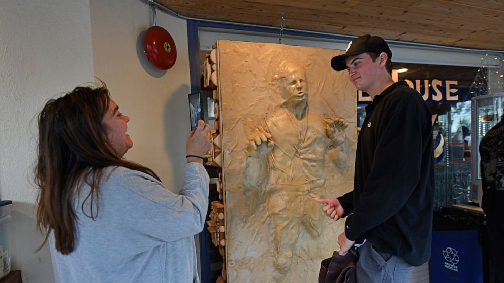 Michelle Heberling, of Benicia, takes a photograph of her son Wesley Heberling with a sculpture of "Star Wars" character Han Solo frozen in carbonite made entirely of bread while at the One House Bakery in Benicia, Calif., Sunday, Oct. 16, 2022. The 